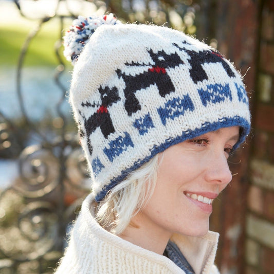 Lady wearing a white bobble beanie with black Radley type dogs.