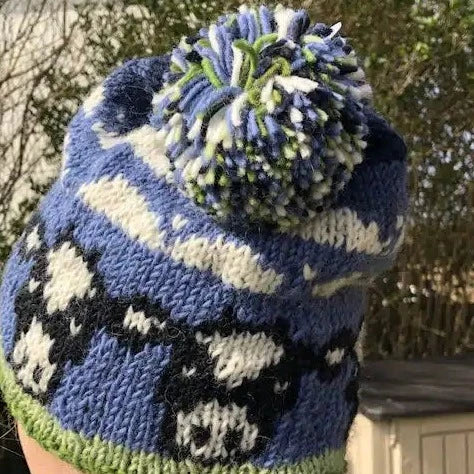 A close-up of a striped Pachamama Dairy Cow Bobble Hat with blue and white colors, featuring a bobble knot on top.