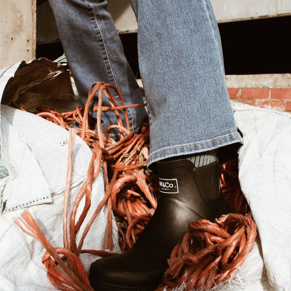 Ankle wellies being worn with boot leg jeans whilst standing on farm yard string